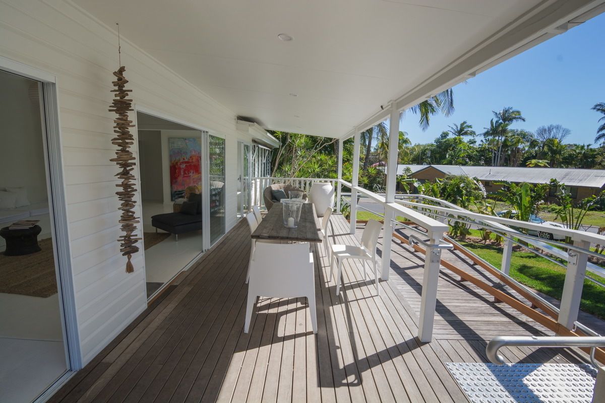 A wooden deck with a white railing, a table, and chairs.