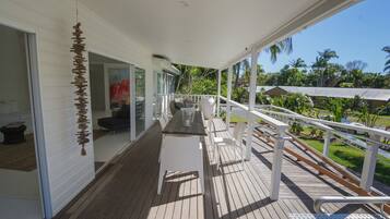 A wooden deck with a white railing, a table, and chairs.