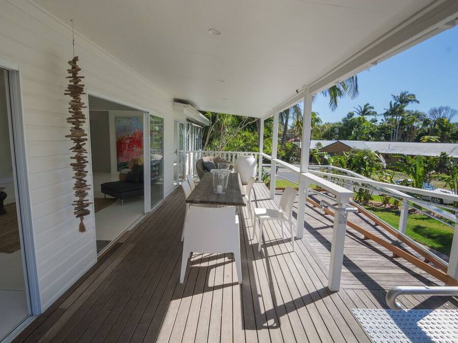 A wooden deck with a white railing, a table, and chairs.