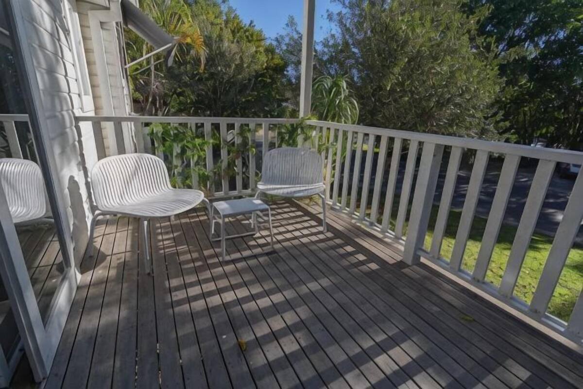 A wooden deck with white railings, two white chairs, and a small table.