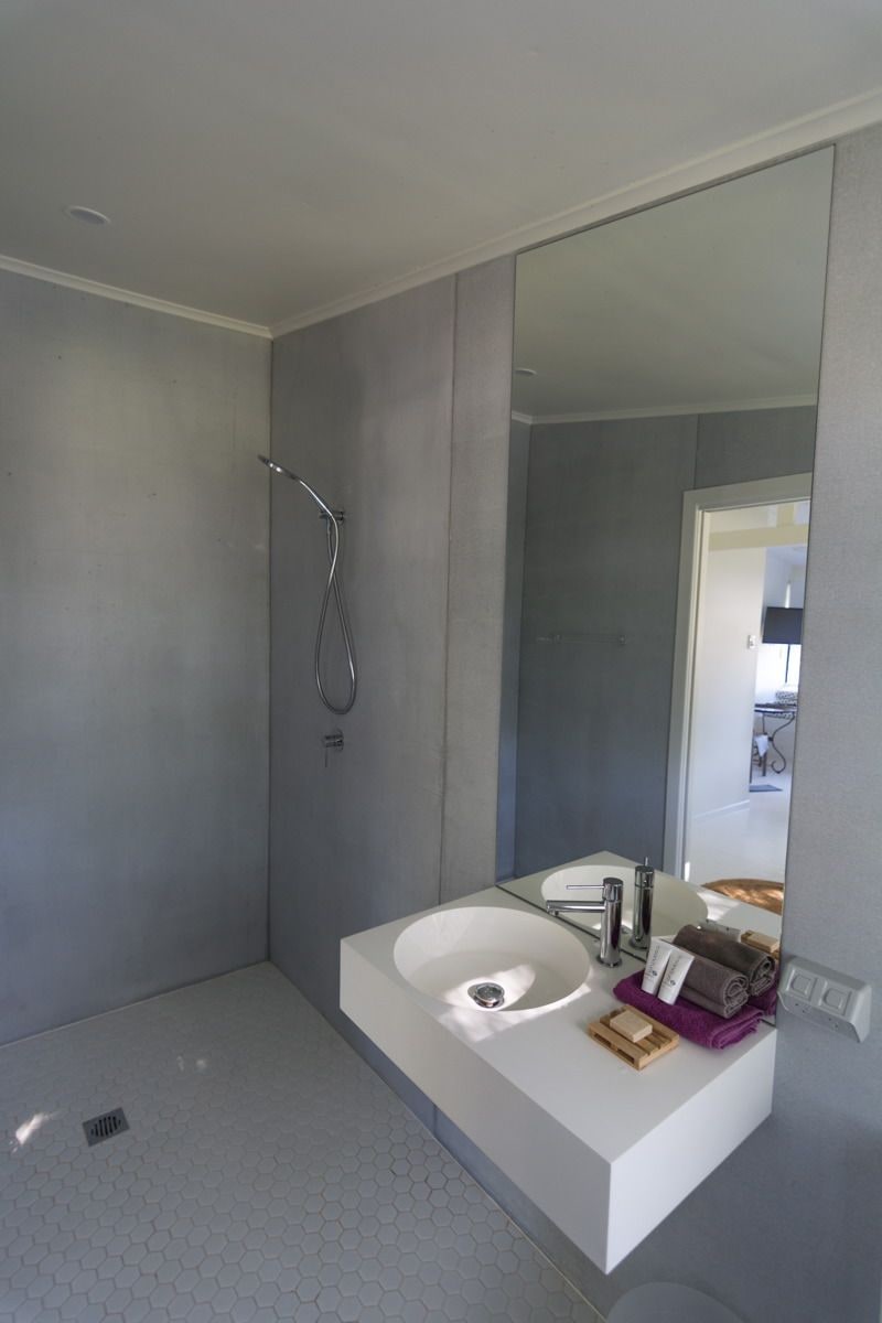 A modern bathroom with a large mirror, a white sink, and a shower.
