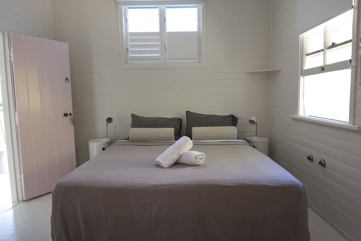 A bedroom with a bed, two bedside tables, a window, and a door.