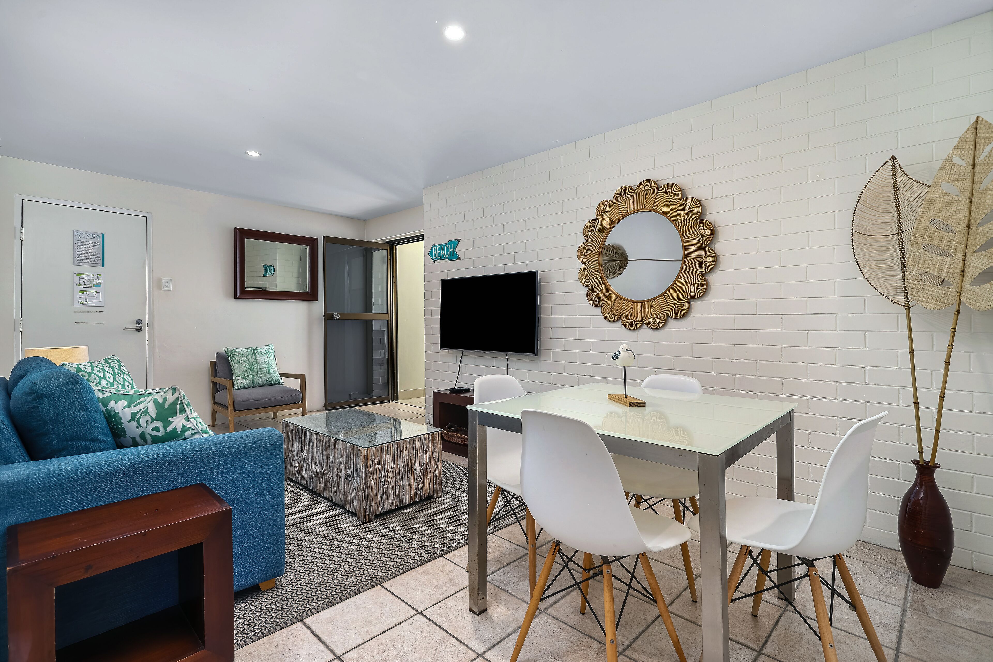 A modern living room with a sofa, coffee table, TV, and a dining area with chairs and a table.
