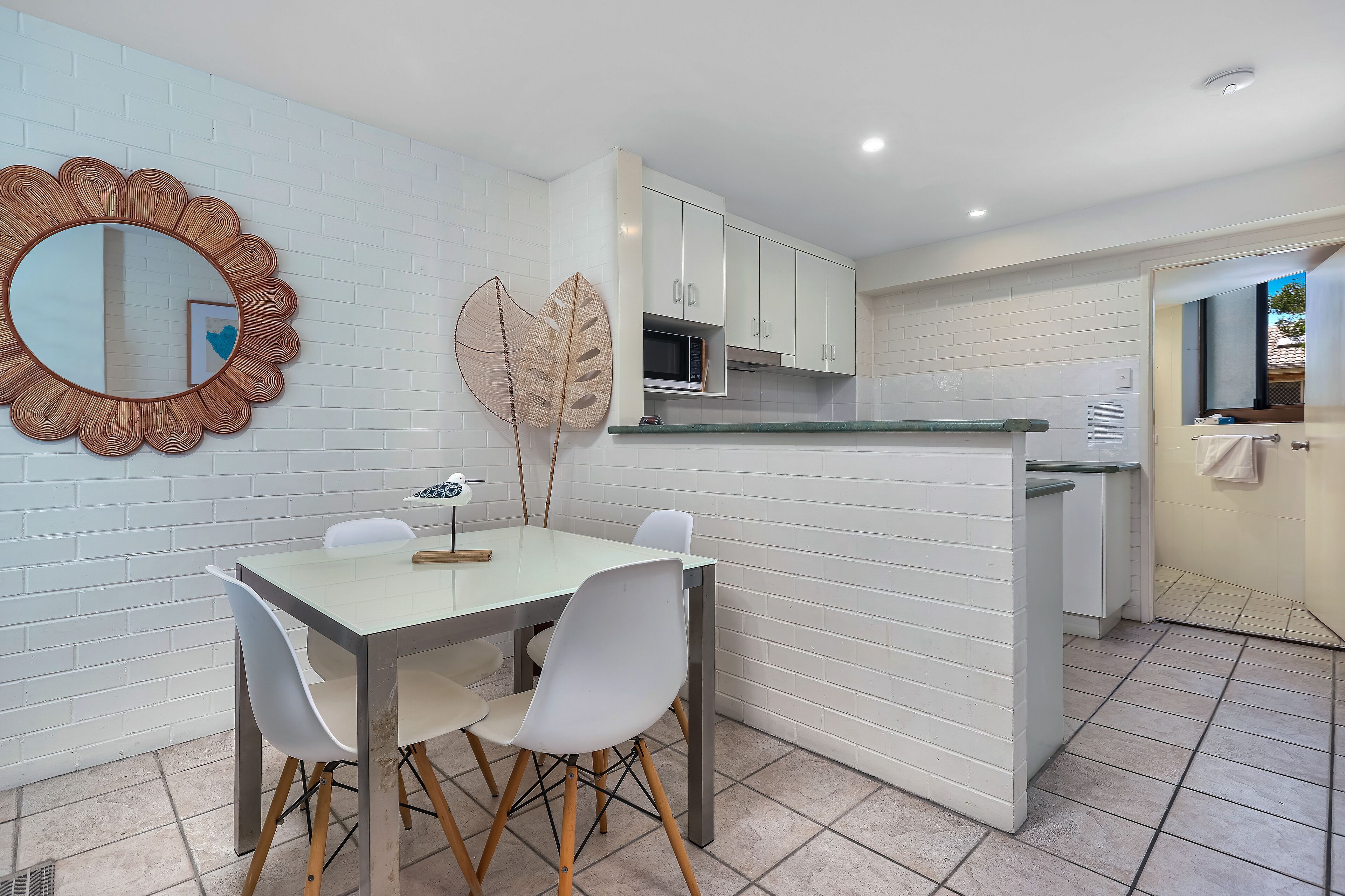 A modern kitchen with white cabinets, a microwave, and a dining area with a table and chairs.