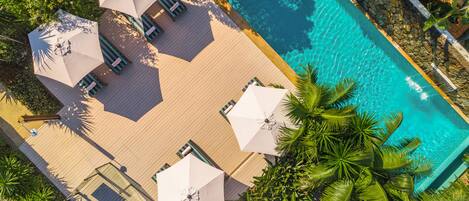 An aerial view of a pool area with lounge chairs and umbrellas.
