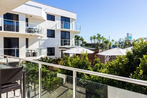 A modern building with multiple balconies, outdoor seating, and lush greenery. - Bayview Beachfront Apartments, in town right on the beach (Byron Bay)