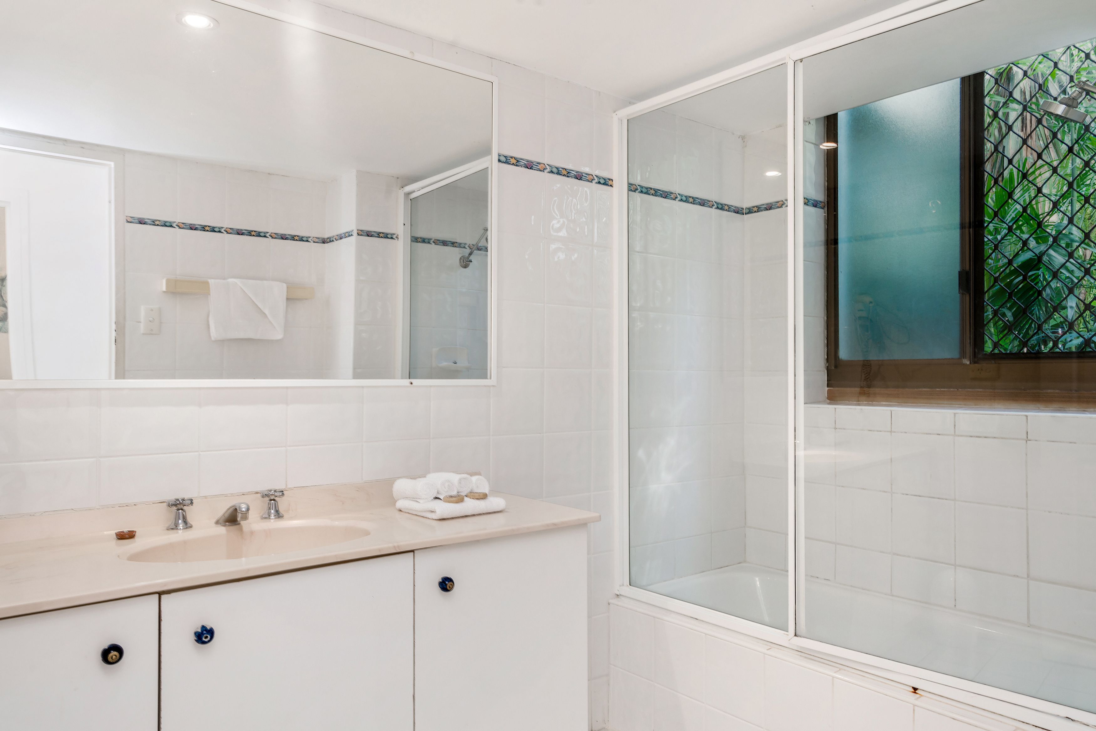 A modern bathroom with a large mirror, a sink, and a shower enclosure.