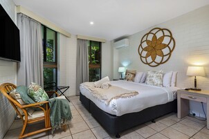 Un dormitorio con cama, una silla, un escritorio y un aire acondicionado de pared.