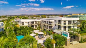Un hotel de varios pisos, con piscina al aire libre y abundante vegetación.