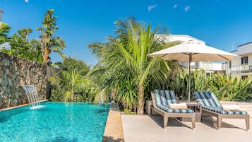 Una piscina al aire libre, sombrillas, sillones reclinables de piscina