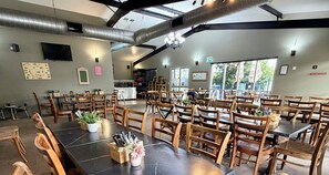 A spacious indoor dining area with high ceilings, exposed ductwork, and natural light from large windows. - Dooleys Springsure Tavern and Motel (Springsure)