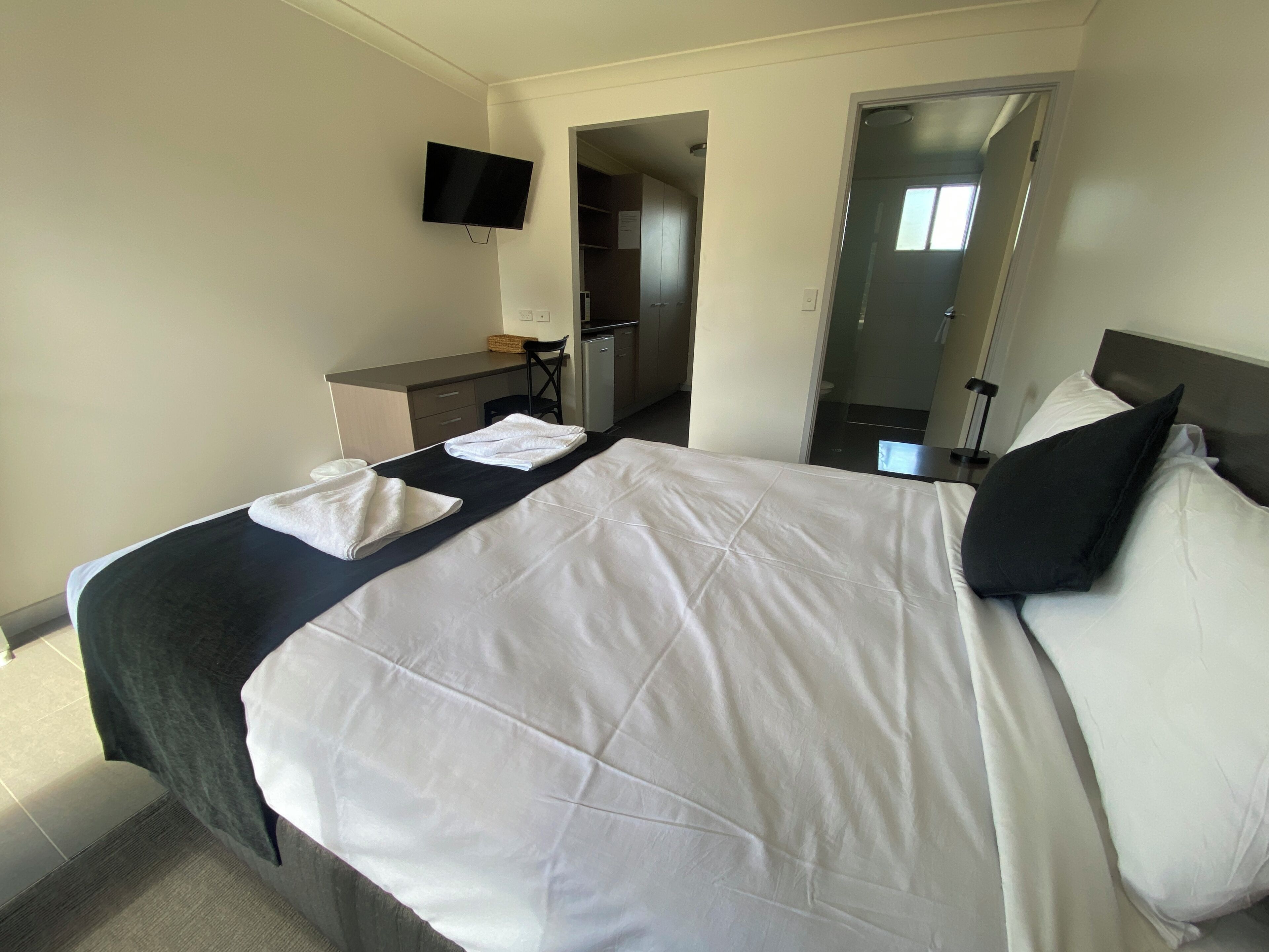 Una habitación de hotel con cama, escritorio, televisor de pantalla plana y espejo.