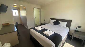A hotel room with a bed, bedside tables, a desk, and a chair.