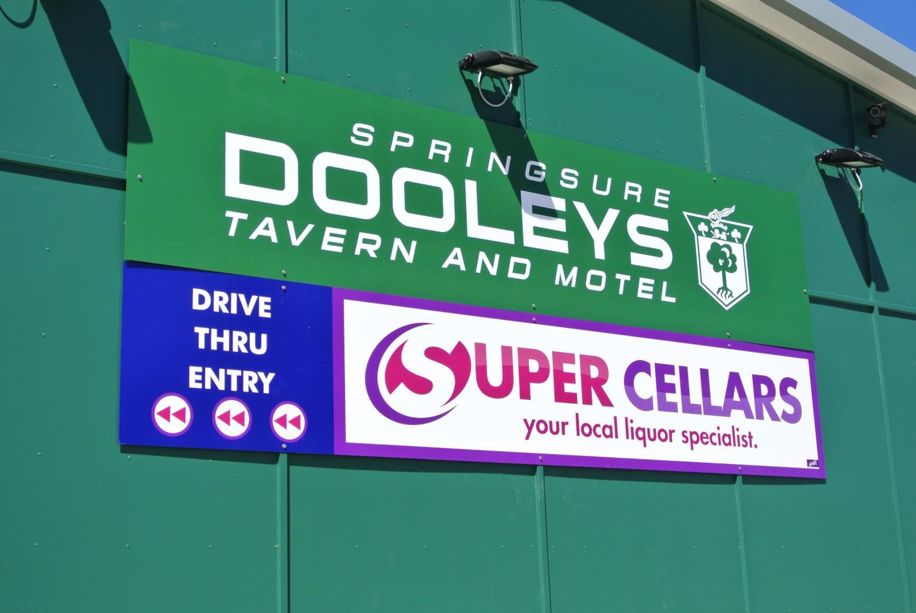 A sign for Springsure Dooley's Tavern and Motel with a Super Cellars liquor specialist advertisement.