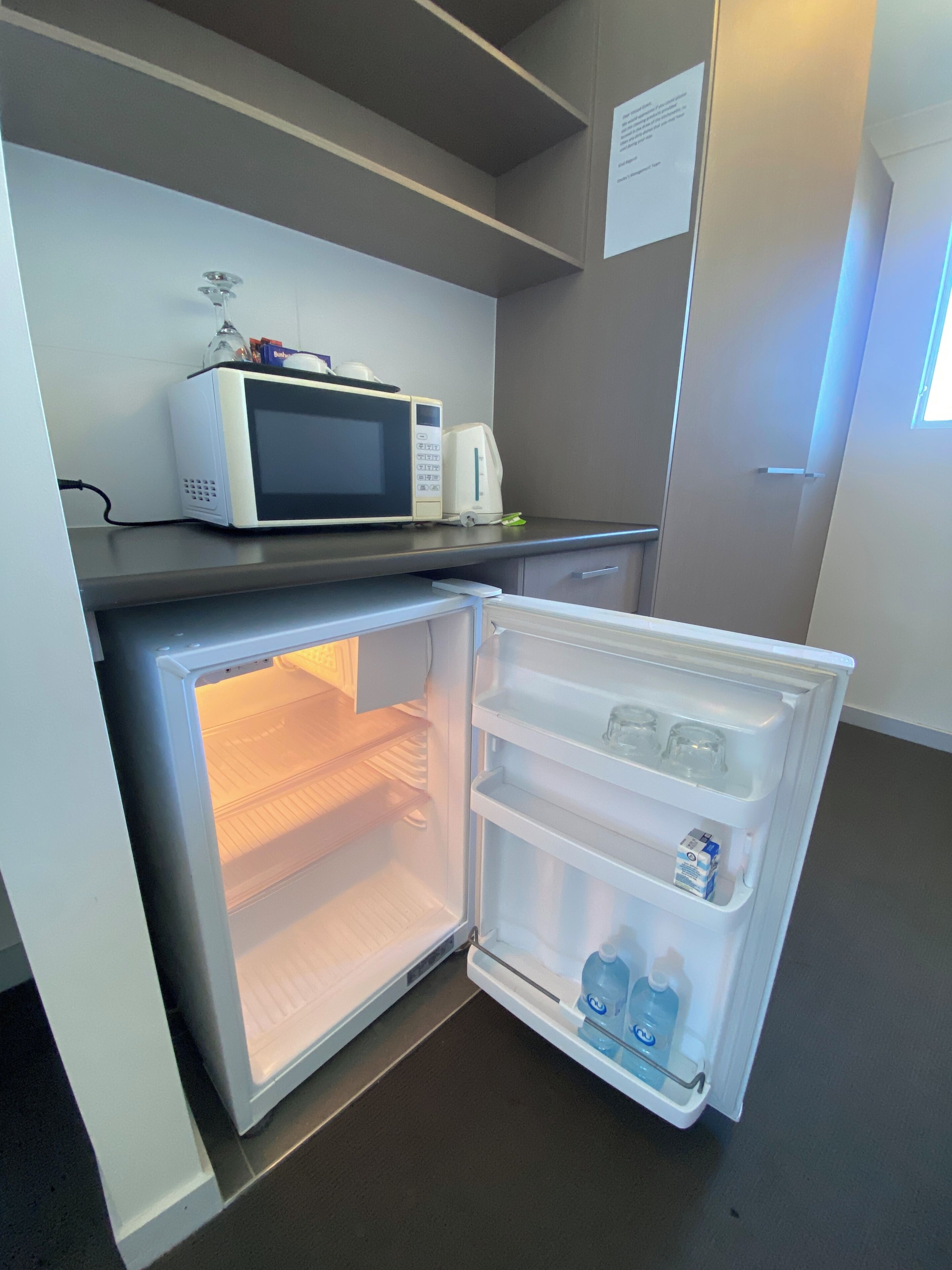 A compact kitchen with a built-in microwave, a refrigerator with a freezer, and a small countertop.