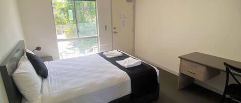 Una habitación de hotel con cama, escritorio, silla, ventana y puerta.