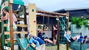 A playground with a slide, climbing structures, and swings.