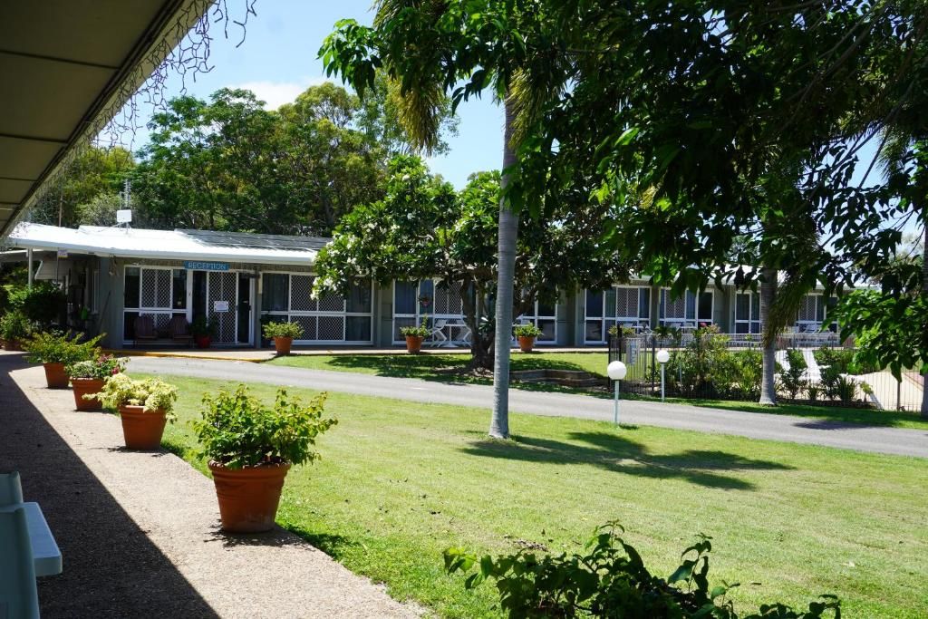 A building with a covered porch, potted plants, and a clear sky.