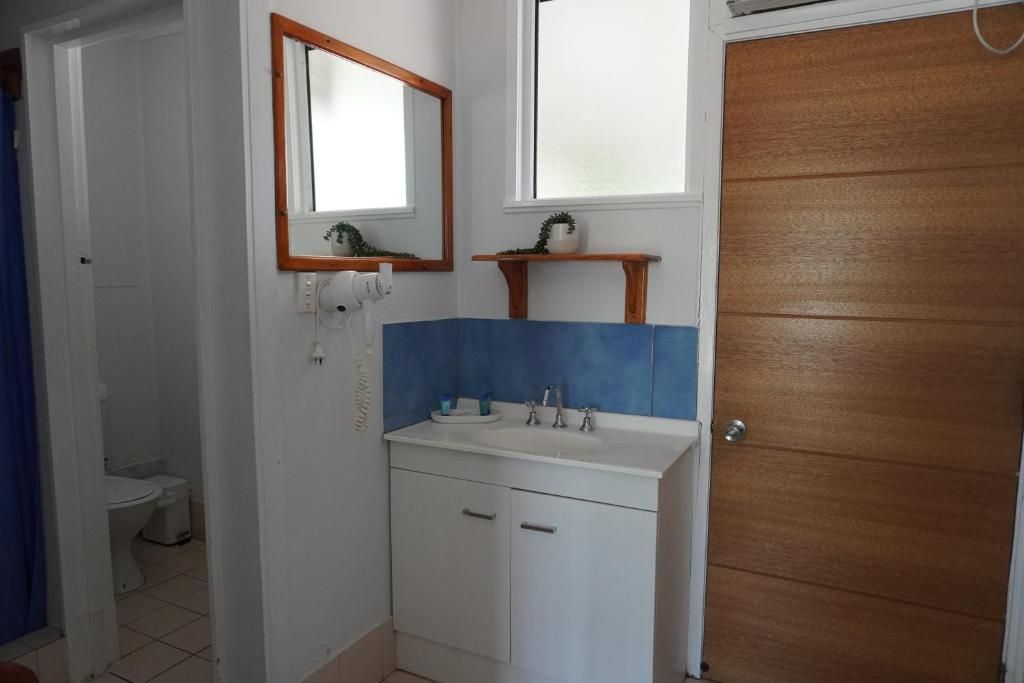 A bathroom with a white sink, a mirror, and a wooden door.