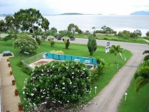 Vista de una zona costera con una carretera, vegetación y una masa de agua al fondo.