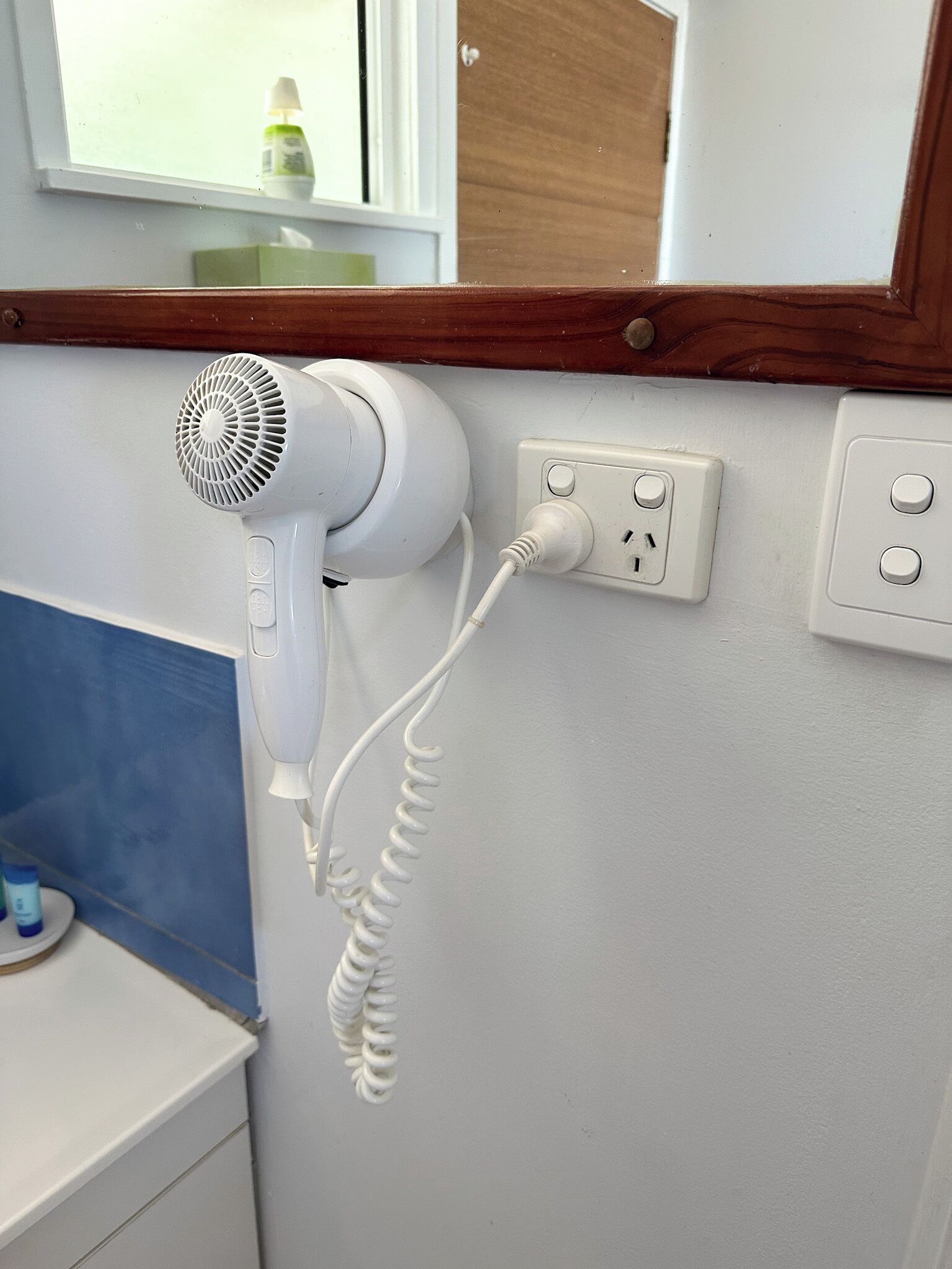 A hair dryer plugged into a wall socket in a bathroom.