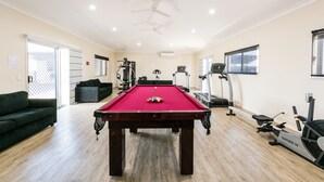 A pool table in a room with a treadmill, exercise bike, and a green sofa. - Athena Studio Units (Roma)
