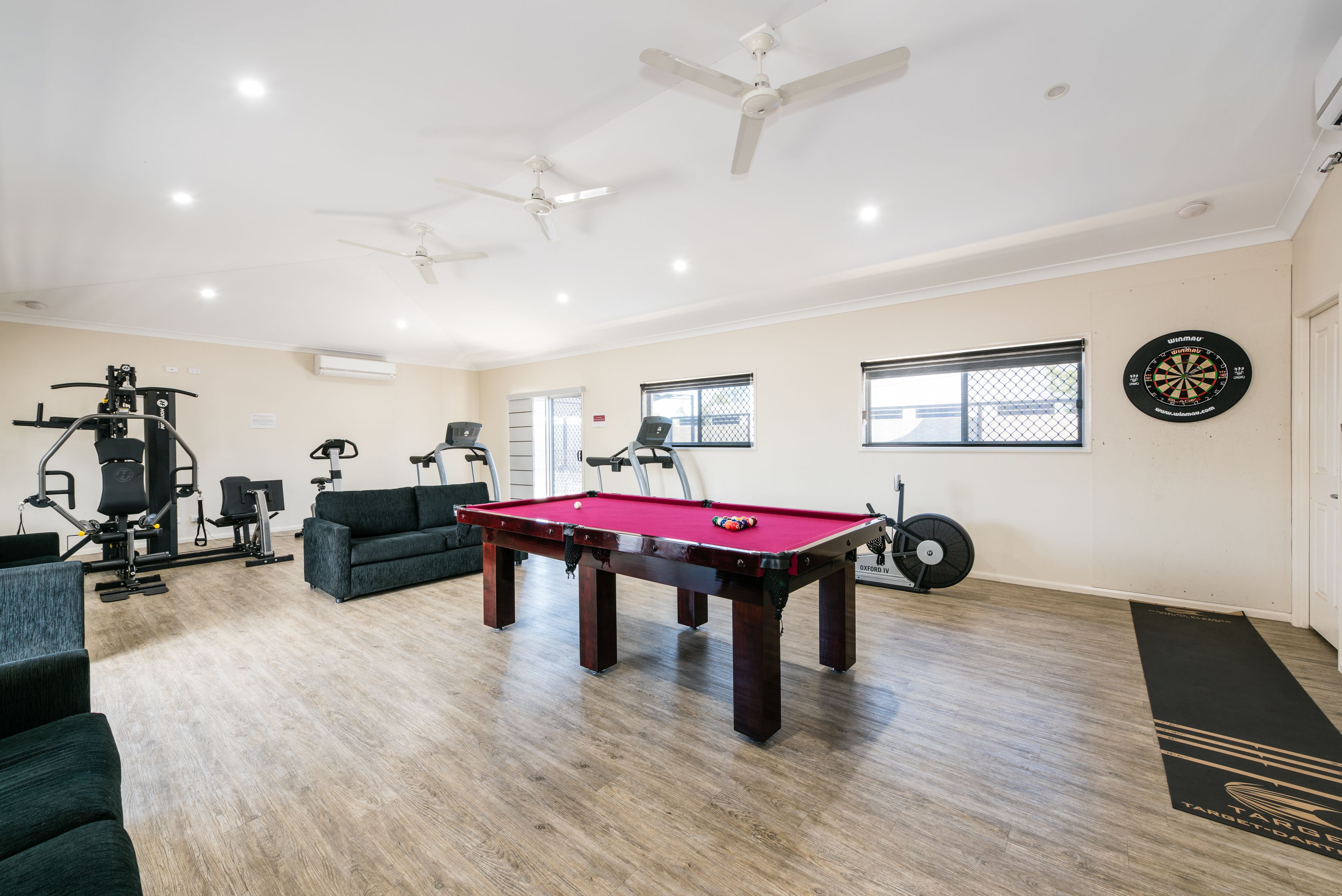 A spacious room with a pool table, exercise equipment, and a dartboard.