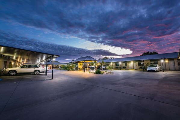 A hotel with a covered outdoor seating area, a carport, and a building with a flat roof. - Athena Studio Units (Roma)