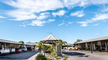 A motel with a central gazebo, parking lot, and multiple rooms.