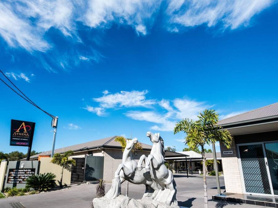 En hotelindgang med en skulptur af en hest og rytter, en klar blå himmel og et skilt der viser, at hotellet er ledigt.