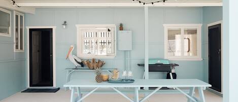 Una habitación azul claro con una puerta y un armario blancos, y una mesa con objetos decorativos.