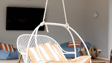 Relax in a stylish space with a wicker swing chair, flat-screen TV, and cozy sofa.