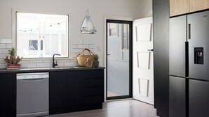 A modern kitchen with a dishwasher, a large window, and a refrigerator. - Blue Water Motel (Kingscliff)