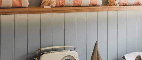 A wooden shelf with a decorative bowl, two towels, a radio, a small figurine, and a book titled "Surf Shacks".