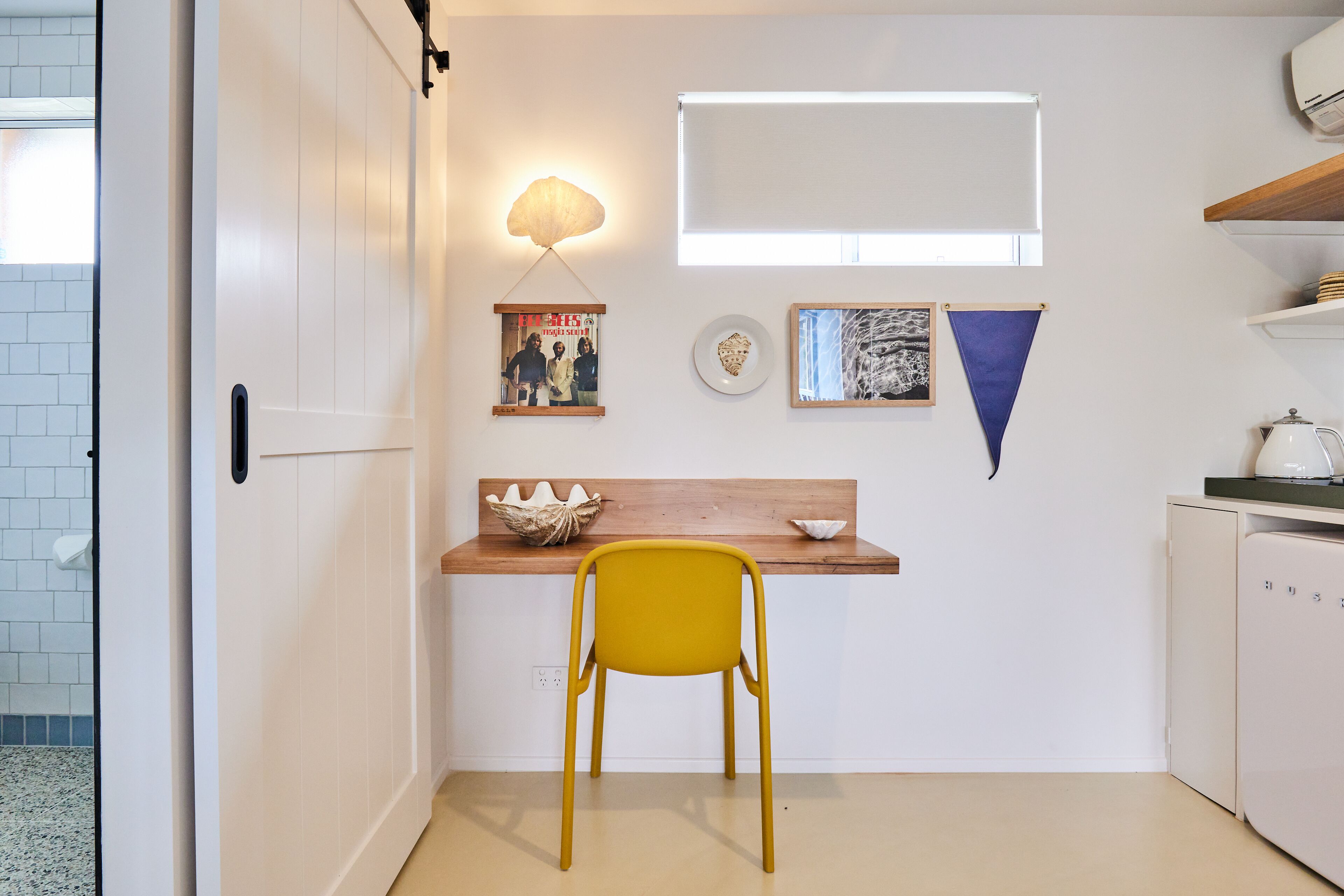 Una cocina compacta con encimera de madera, una silla amarilla y un refrigerador blanco.