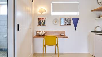 Una cocina compacta con encimera de madera, una silla amarilla y un refrigerador blanco.
