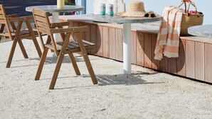 A beachfront property with a covered outdoor seating area, wooden chairs, and a table. - Blue Water Motel (Kingscliff)