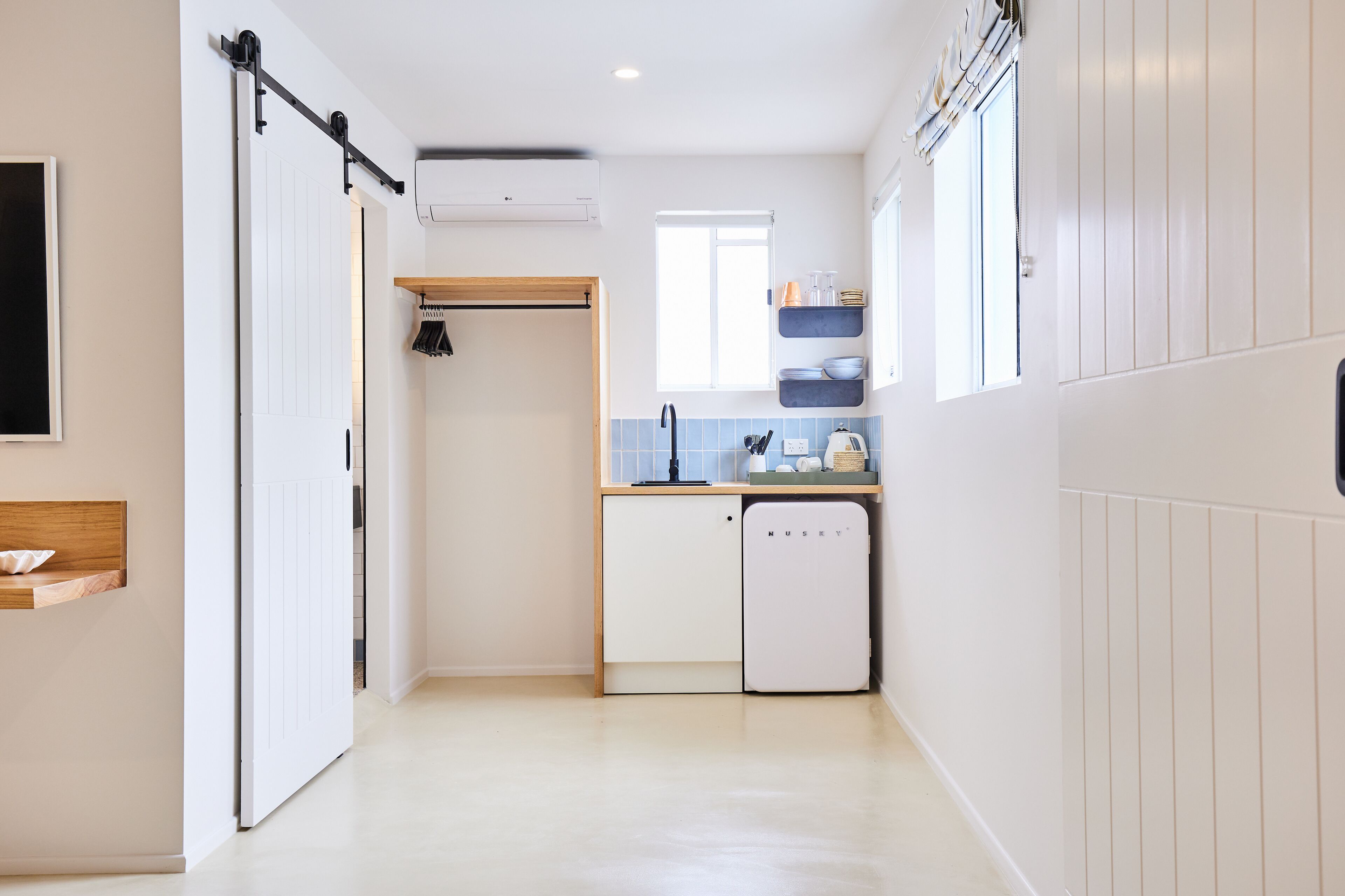 A compact kitchen with a built-in dishwasher, a wooden cabinet, and a window providing natural light.