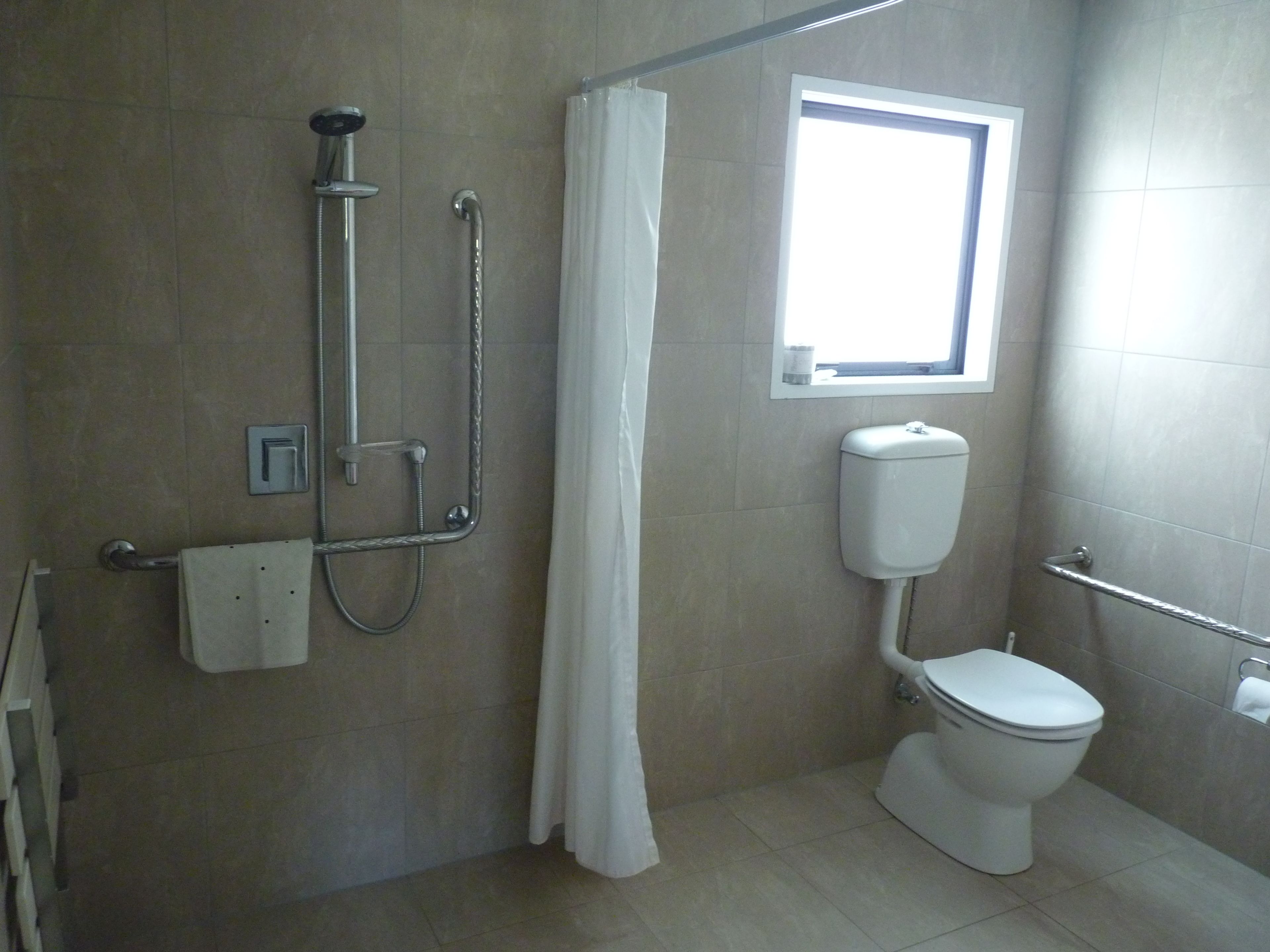 A bathroom with a shower, toilet, and a window.