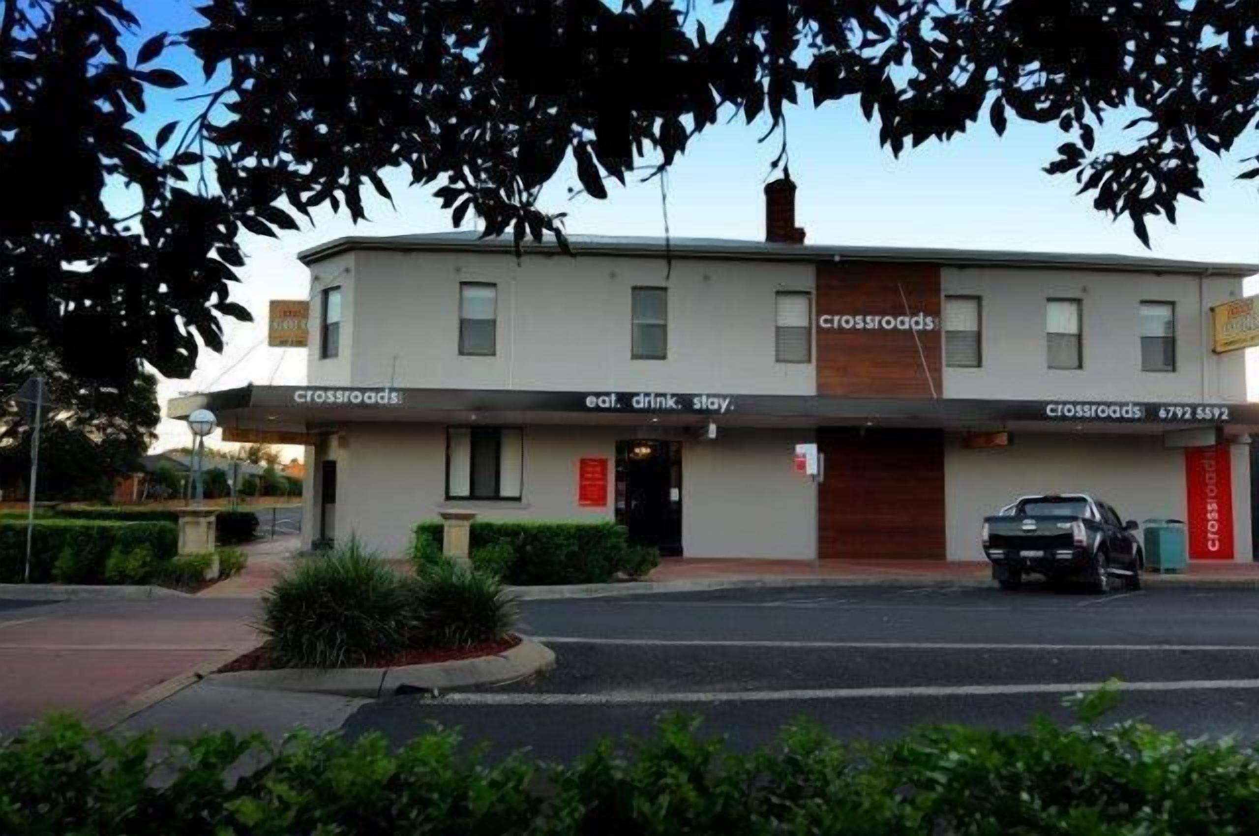 A two-story building with a sign reading "crossroads" and "eat. drink. stay."