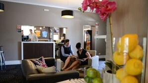 A hotel lobby with a reception desk, seating area, and a decorative plant. - Crossroads Hotel Narrabri (Narrabri)