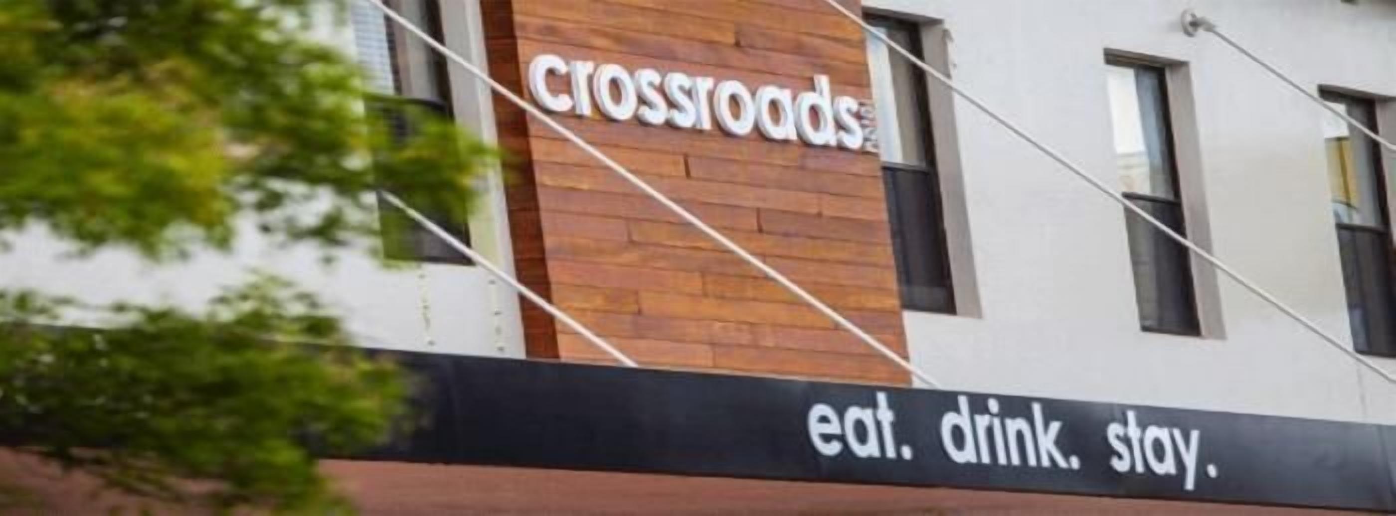 Un edificio con un letrero que dice "crossroads" y el eslogan "eat. drink. stay".
