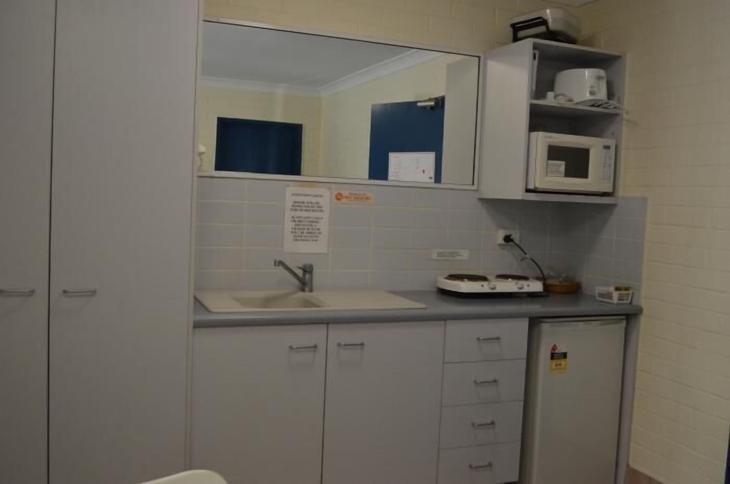 A small kitchenette with a microwave, a sink, and a cabinet.