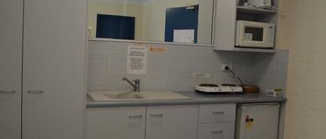 A small kitchenette with a microwave, a sink, and a cabinet.