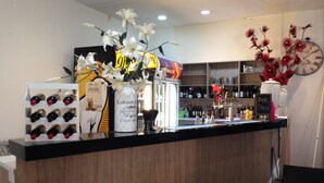 Una zona de bar con mostrador, botellas de vino, un jarrón con flores y un reloj en la pared.