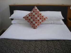 A neatly made bed with white linens and a patterned pillow. - Burkes Hotel Motel (Yarrawonga)
