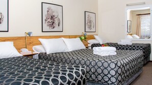A hotel room with two beds, a wooden headboard, and artwork on the walls. - Aalbany Motel (Narrabri)