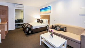 Una habitación de hotel con cama, sofá, mesa de centro y un cuadro en la pared.