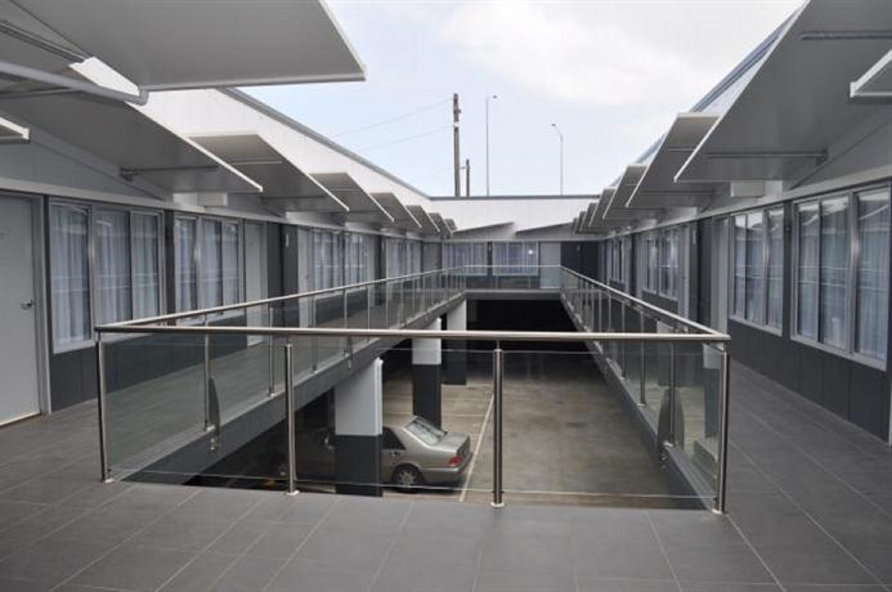 Un edificio moderno con una zona de estacionamiento de paredes de vidrio y un coche dentro.