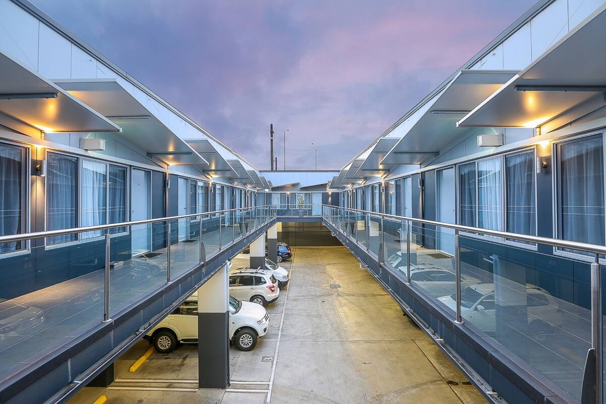 A modern building with a covered parking area and a glass walkway.